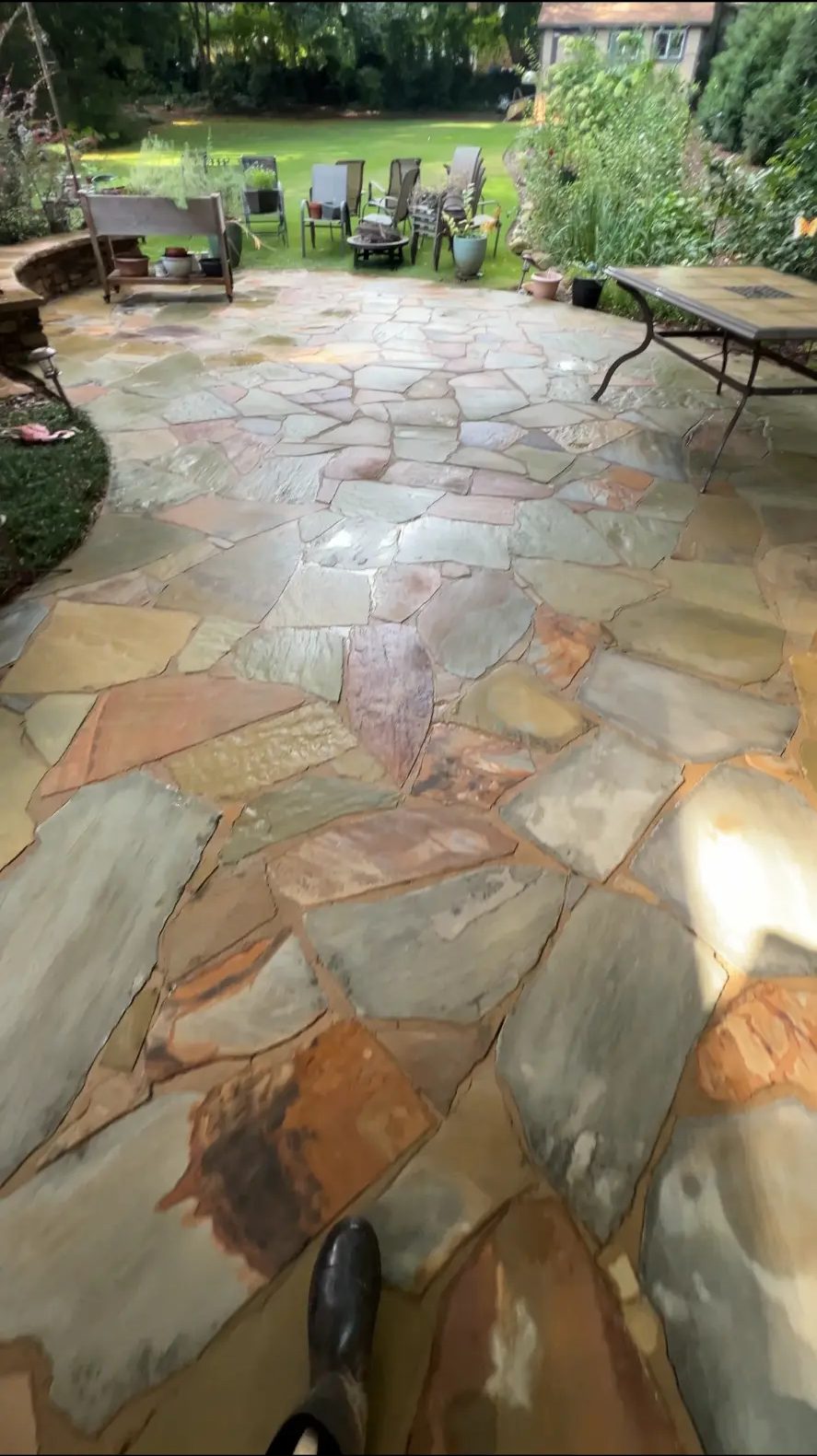 Freshly cleaned flagstone patio beside a backyard garden