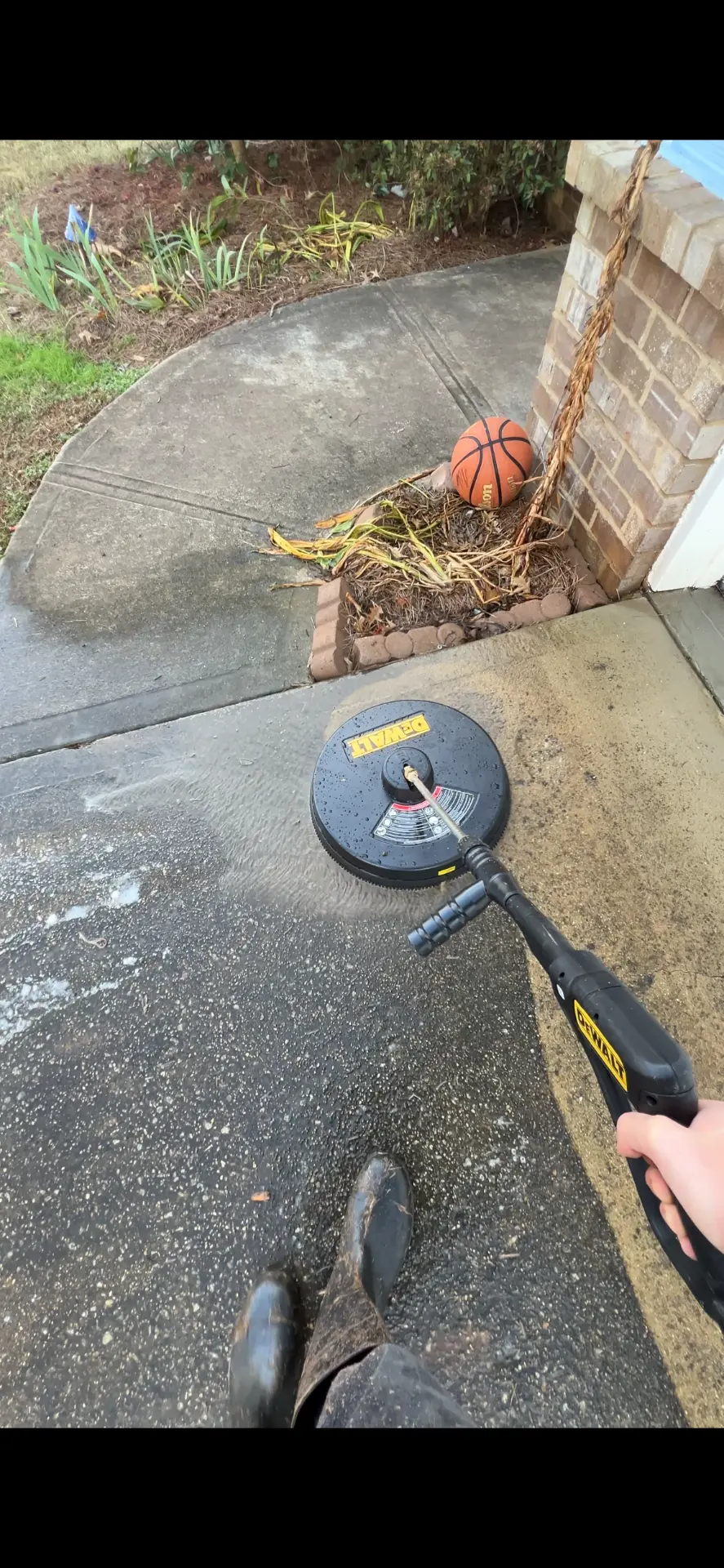 Surface cleaner cutting through dirt on a concrete driveway